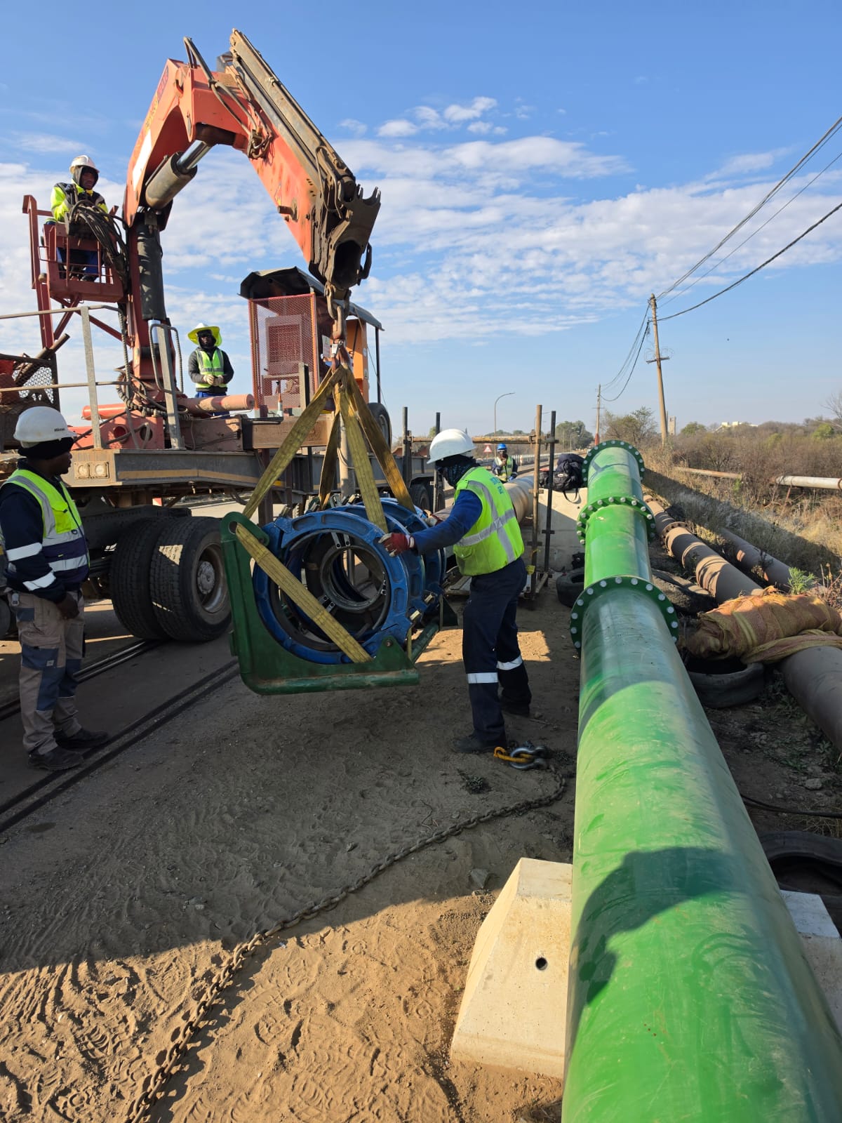 Wetpipe crew lifting a butt-fusion machine onto a slurry pipeline bridge crossing